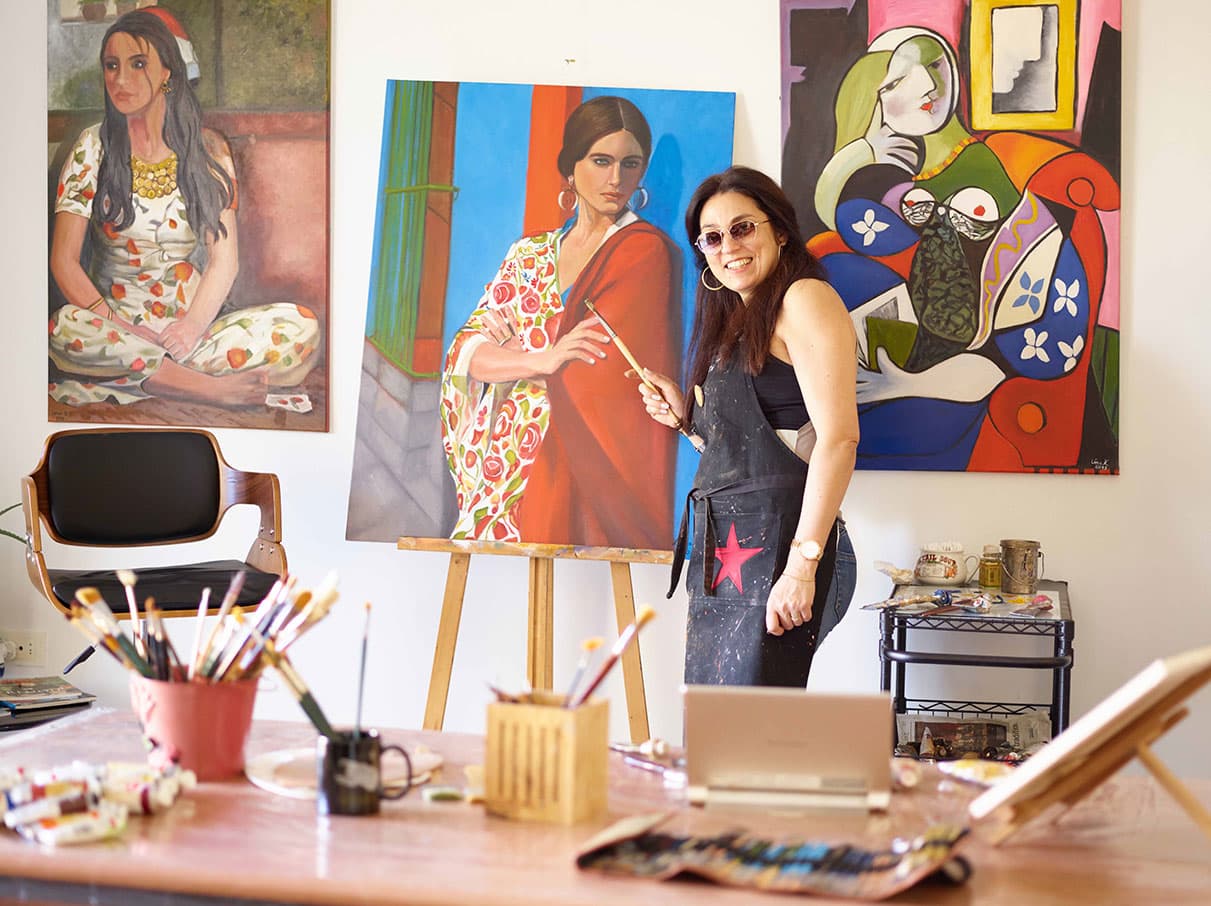 Léna Khalifeh in the studio, standing with a finished portrait